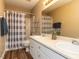 Well-lit bathroom features double sinks, wood-look floors, and shower with modern grey striped curtain at 212 Walnut Creek Dr, Clayton, NC 27520
