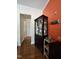 Hallway featuring hardwood floors, access to a room, display cabinet and a vibrant orange accent wall at 2132 Royal Berry Ct, Cary, NC 27511
