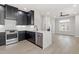 Open-concept kitchen with black cabinets, stainless steel appliances, island, and light wood floors adjoining living space at 226 Woodsborough Pl, Raleigh, NC 27601