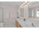 Bright bathroom with double sinks, wood cabinetry, and two large mirrors with lights above each vanity at 3003 Cregler Dr, Apex, NC 27502