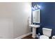 Half bathroom with blue accent wall, pedestal sink, and hardwood floors at 319 Brinkley Cir, Mebane, NC 27302