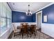 A dining room with navy blue walls, white wainscoting, and a modern chandelier over a wooden table at 319 Brinkley Cir, Mebane, NC 27302
