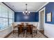 A dining room with navy blue walls, white wainscoting, and a modern chandelier over a wooden table at 319 Brinkley Cir, Mebane, NC 27302