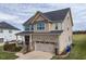 Two-story home with a brick and tan siding exterior, an attached garage and a well-manicured front yard at 319 Brinkley Cir, Mebane, NC 27302