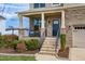 A cozy front porch featuring brick columns, a black metal railing, and neatly trimmed landscaping at 319 Brinkley Cir, Mebane, NC 27302