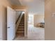 Hallway with carpeted staircase and neutral walls leading to a carpeted living room and a thermostat at 319 Brinkley Cir, Mebane, NC 27302