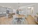 Bright dining area with round wooden table, white chairs, and modern chandelier next to kitchen with gray cabinets at 3408 Dropseed Dr, Apex, NC 27502