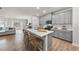 Open-concept kitchen with gray cabinets, quartz countertop island, and stainless steel appliances connects to the living area at 3408 Dropseed Dr, Apex, NC 27502