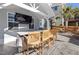 Covered outdoor kitchen boasts a TV, stone bar, and seating for entertaining at 3633 Jordan Shires Dr, New Hill, NC 27562