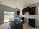 Bright kitchen with dark cabinets, stainless appliances, an island, and sliding doors to the backyard at 394 Springtooth Dr, Zebulon, NC 27597