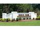 Welcoming entrance to Baker Farm featuring a white brick wall with black lettering and lush landscaping at 40 Granite Falls Way, Youngsville, NC 27596