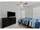A cozy bedroom with a ceiling fan and a large television on a black dresser at 402 Homestead Park Dr, Apex, NC 27502