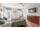 Cozy bedroom with a ceiling fan, mounted TV, and a large window for natural light at 408 E Maple Ave, Holly Springs, NC 27540