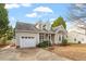 Charming home featuring an attached garage, inviting front porch, and a well-manicured front yard on a sunny day at 408 E Maple Ave, Holly Springs, NC 27540