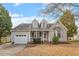 Charming two-story home features an attached garage, inviting front porch, and a well-manicured front yard on a sunny day at 408 E Maple Ave, Holly Springs, NC 27540