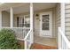 Close up of a covered front porch with white railing, a white front door, and the house number at 408 E Maple Ave, Holly Springs, NC 27540