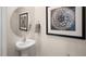 Stylish powder room with a pedestal sink, round mirror, and decorative artwork at 416 Belgian Red Way, Wake Forest, NC 27587