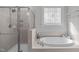 Bright bathroom featuring a soaking tub, enclosed shower, and decorative glass block window for added elegance at 4228 Bibleway Ct, Holly Springs, NC 27540