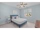 Cozy bedroom with a light blue paint, ceiling fan, window, and a comfortable queen bed at 4228 Bibleway Ct, Holly Springs, NC 27540
