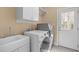 Well-lit laundry room featuring modern washer, dryer, utility sink, storage cabinets, and convenient access to an exterior door at 4228 Bibleway Ct, Holly Springs, NC 27540