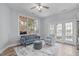 Cozy living room with ample light, features a plush sofa and stylish decor, enhanced by a modern ceiling fan at 4228 Bibleway Ct, Holly Springs, NC 27540