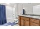 Well-lit bathroom with tile floors, a wood vanity, and a shower and tub combo with blue curtain at 424 Hopwood Way Way, Apex, NC 27523