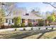Inviting one-story brick home with well-maintained landscaping, bright yellow door, and a gravel driveway at 4605 Erwin Rd, Durham, NC 27705