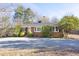Charming brick home with mature trees, a welcoming yellow door, and a gravel driveway at 4605 Erwin Rd, Durham, NC 27705