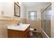 Bathroom featuring a wood vanity, shower with glass door, and tiled walls with a window at 4816 Stafford Dr, Durham, NC 27705