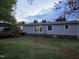 View of the backyard with a well-kept lawn and the exterior of the single story home at 5636 Thom Rd, Mebane, NC 27302