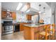 Kitchen with a skylight, stainless steel appliances, wood cabinets, a breakfast bar, and stylish lighting at 5636 Thom Rd, Mebane, NC 27302