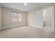 Neutral bedroom featuring light-colored walls, window and door to the bathroom at 6106 Bent Oak Dr, Durham, NC 27705
