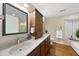 Bright bathroom with dual sinks, wood cabinets, granite counters and decorative wall mirror with a window seat and tub at 6301 King Lawrence Rd, Raleigh, NC 27607