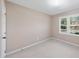 Bright bedroom with neutral walls, carpet, and a sun-filled window overlooking the front yard at 6301 King Lawrence Rd, Raleigh, NC 27607