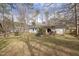 Wide backyard with a wooden deck, firepit, and a full canopy from many surrounding trees at 6913 Baywood Dr, Raleigh, NC 27613