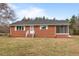 A cozy one-story brick house with white trim, an enclosed porch, and manicured landscaping at 7415 Old Oxford Rd, Bahama, NC 27503