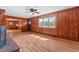 Sun-filled living room boasting wood paneled walls, a fireplace and seamless flow to the kitchen at 7415 Old Oxford Rd, Bahama, NC 27503