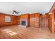 Spacious living room with wood paneled walls, a ceiling fan, and a brick fireplace at 7415 Old Oxford Rd, Bahama, NC 27503