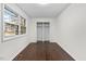 A bedroom with hardwood floors and a large window overlooking the front yard and double-door closet at 7725 Longstreet Dr, Raleigh, NC 27615