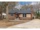 Charming brick ranch home featuring a black roof, brick chimney, and inviting front porch at 7725 Longstreet Dr, Raleigh, NC 27615
