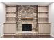 Inviting fireplace featuring stone surround, a wood mantle, and custom built in shelving at 7725 Longstreet Dr, Raleigh, NC 27615