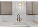 Kitchen sink with quartz countertops, subway tile backsplash, and modern faucet fixtures at 7725 Longstreet Dr, Raleigh, NC 27615
