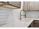 Kitchen sink featuring quartz countertops, subway tile backsplash, and sleek, modern fixtures at 7725 Longstreet Dr, Raleigh, NC 27615