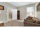 Neutral living room features a brown sofa, a window with white trim, and access to the bathroom at 823 Atticus Way, Durham, NC 27703