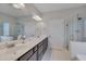 Main bathroom features dual sinks, a large mirror, vanity lighting and a tiled shower at 84 Nonabell Ln, Four Oaks, NC 27524