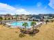 Aerial view of a community pool with a clubhouse, palm trees, lounge chairs, and neighborhood homes around the perimeter at 94 Fawn Hill Ct, Garner, NC 27529