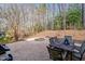Backyard patio area with a fire pit, outdoor table with chairs, and wooded area at 94 Fawn Hill Ct, Garner, NC 27529