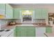 This kitchen is bright and features an above-the-sink window and green cabinets at 1008 Torredge Rd, Durham, NC 27712