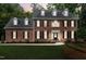 A two-story brick home with black shutters is illuminated by the warm glow of twilight at 102 Legault Dr, Cary, NC 27513