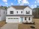 Charming two-story home featuring white siding, blue front door, attached two car garage, and well-maintained landscaping at 1026 Janiskee Rd, Durham, NC 27703